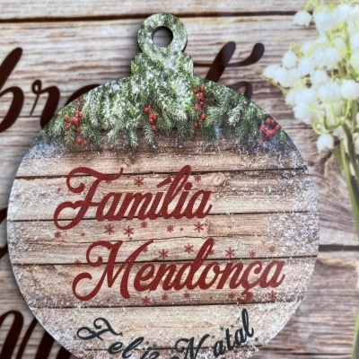 Medalha decorativa de madeira com texto 'Família Mendonça Feliz Natal' e decoração de pinheiro e bagas vermelhas