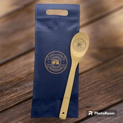 Colher de madeira e saco azul com selo dourado sobre mesa de madeira