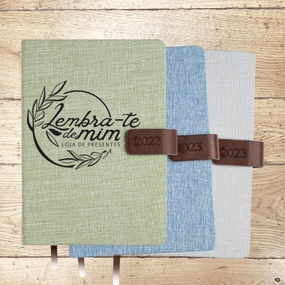 Três agendas com capas de tecido e fechos castanhos com ano 2023
