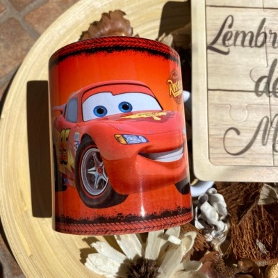 Cofre cilíndrico vermelho com personagem Relâmpago McQueen, base de madeira com flores decorativas ao redor