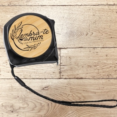 Fita métrica preta com tampa em madeira clara e texto 'Lembra-te de mim'
