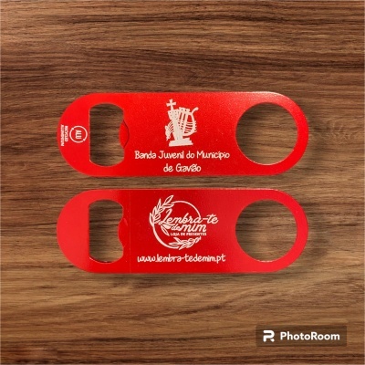 Dois abridores de garrafas vermelhos com texto branco, sobre madeira.