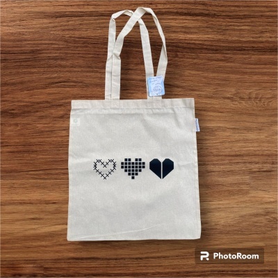 Saco branco com estampa de três corações pretos e alças longas sobre madeira