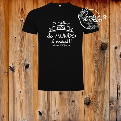 T-shirt preta com texto branco 'O Melhor PAI do MUNDO é meu!!!' pendurada em parede de madeira