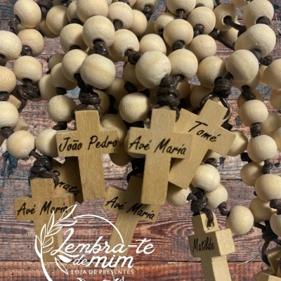 Colares de contas de madeira com cruzes e nomes personalizados sobre fundo de madeira