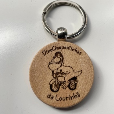 Porta-chaves redondo de madeira com desenho de dinossauro a andar de mota e texto gravado
