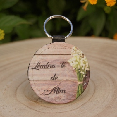 Chaveiro redondo com frase e flores sobre superfície de madeira clara