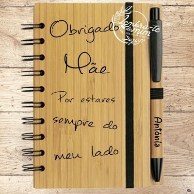 Caderno com capa de madeira clara e caneta personalizadas, texto dedicado à mãe