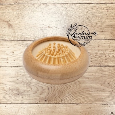 Escova de madeira redonda com cerdas sobre superfície de madeira clara e texto 'Lembra-te de mim'