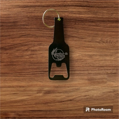 Chaveiro abre-garrafas preto com texto branco sobre superfície de madeira