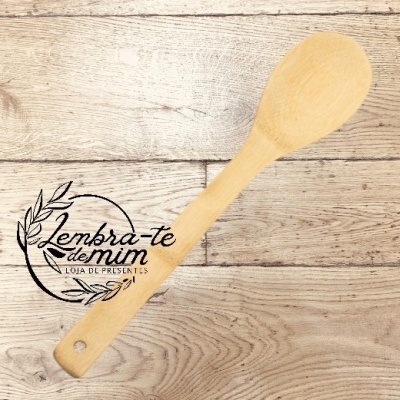 Colher de pau clara com cabo liso sobre mesa de madeira