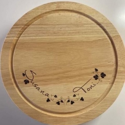 tabuleiro redondo de madeira clara com gravação artística de nomes e folhas