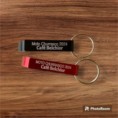 Dois porta-chaves abre-garrafas metálicos preto e vermelho com texto branco sobre madeira