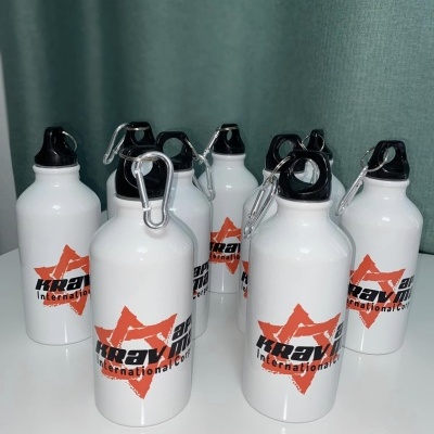 Sete garrafas de água brancas com tampas pretas e logótipo 'krav International' em fundo branco