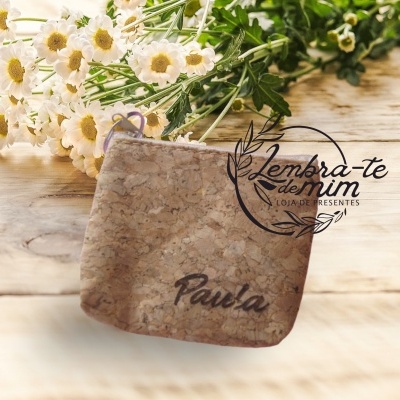 Bolsa de cortiça com o nome Paula, flores brancas e logótipo de loja ao fundo