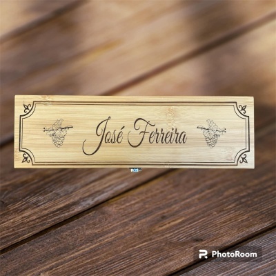 Caixa de madeira clara gravada com nome José Ferreira e cachos de uvas