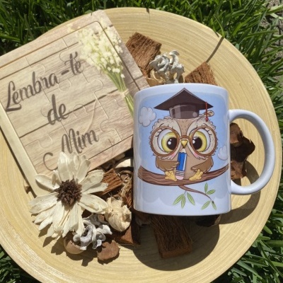 Conjunto com caneca branca decorada, quadro puzzle de madeira e flor seca em prato redondo sobre relva