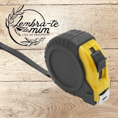 Trena de fita métrica preta e amarela com fita metálica estendida sobre fundo de madeira