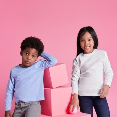 Crianças com camisolas de manga comprida em fundo cor de rosa junto a blocos cor de rosa