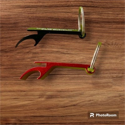 Dois abridores de garrafas de metal, um vermelho e outro verde escuro, com argolas metálicas, sobre superfície de madeira.