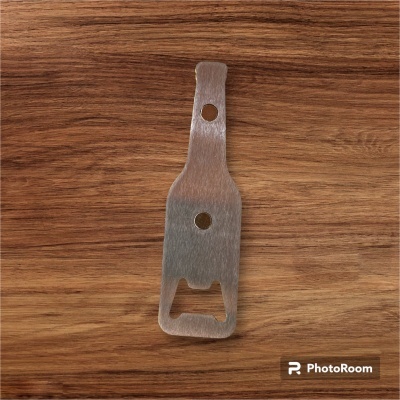 Abridor de garrafas metálico em forma de garrafa sobre superfície de madeira