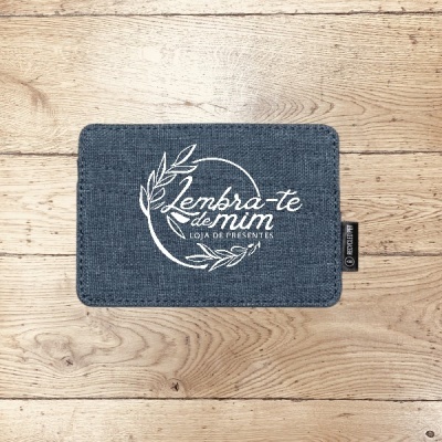 Carteira azul escura de tecido com bordado branco e etiqueta preta sobre fundo de madeira clara