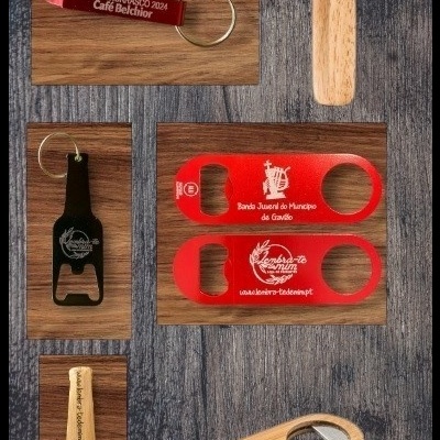 Abridores de garrafas de vários materiais e cores com textos promocionais sobre fundo de madeira