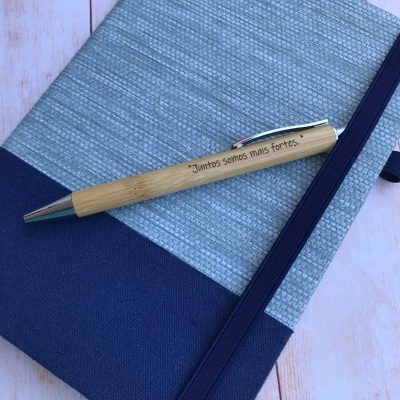 Agenda com capa azul e cinza com caneta de madeira com gravação