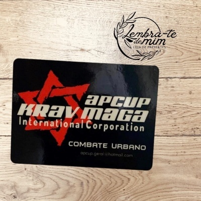 Adesivo preto com texto em branco e vermelho sobre fundo de madeira claro