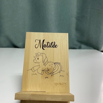 Suporte de telemóvel de madeira clara com texto e desenho gravados