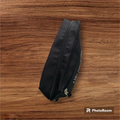 Estojo escolar preto em nylon com fecho de correr sobre mesa de madeira clara