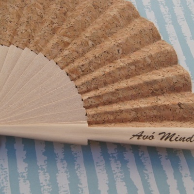 Leque de madeira e cortiça com inscrição Avó Minda sobre fundo listrado azul e branco