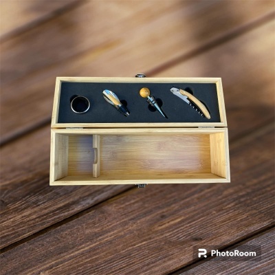 Conjunto de acessórios para vinho em caixa de madeira sobre mesa de madeira.