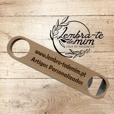 Abridor de garrafas em madeira clara com texto gravado colocado sobre superfície de madeira