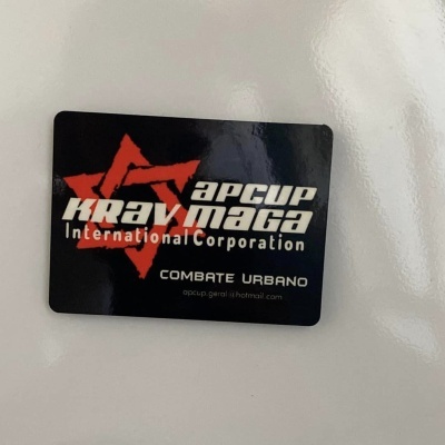 Cartão preto com texto branco e vermelho e estrela vermelha com informações de Krav Maga.