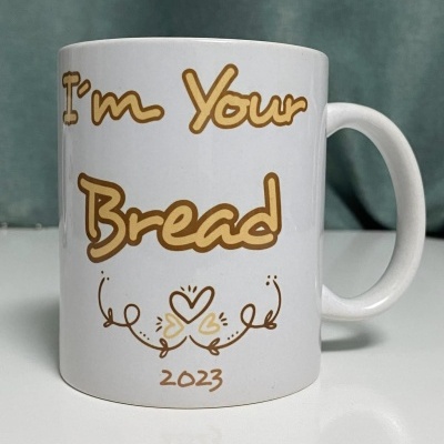 Caneca branca com texto e decoração castanha clara sobre fundo verde.