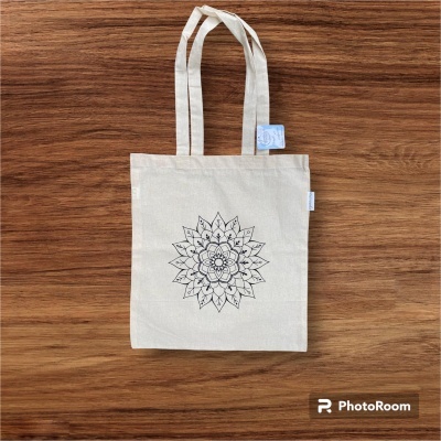 Saco tote de tecido cru com padrão floral geométrico preto sobre madeira