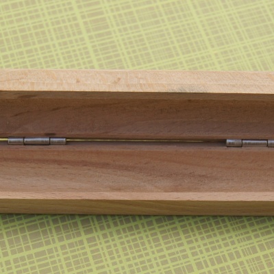 Estojo de madeira natural aberto sobre superfície verde quadriculada