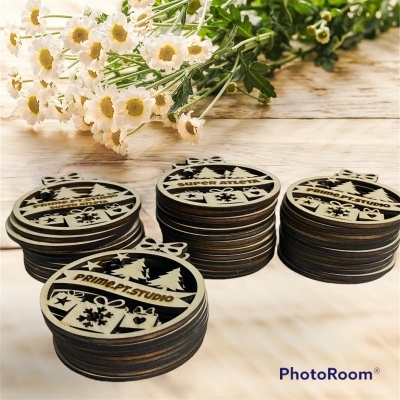 Ornamentos de madeira natalícios redondos com padrões a laser empilhados sobre mesa clara com flores ao fundo