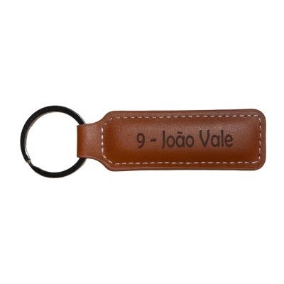 Porta-chaves em pele castanha com texto '9 - João Vale' e aro metálico prateado