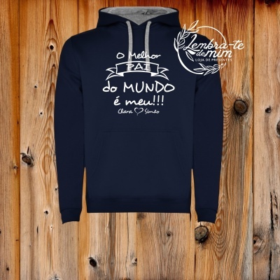 Sweatshirt azul-escuro com capuz e texto branco sobre fundo de madeira.