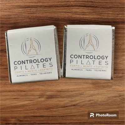 Dois chocolates embalados brancos com texto e símbolo dourado num fundo de madeira