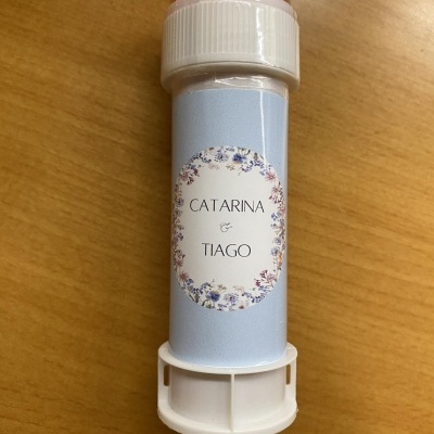 Recipiente branco com tampa rosa e etiqueta azul com texto e flores.