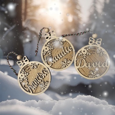 Três enfeites de Natal redondos em madeira com nomes personalizados e flocos de neve