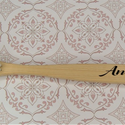 Escova de dentes de bambu com nome Andreia sobre fundo decorativo em tecido