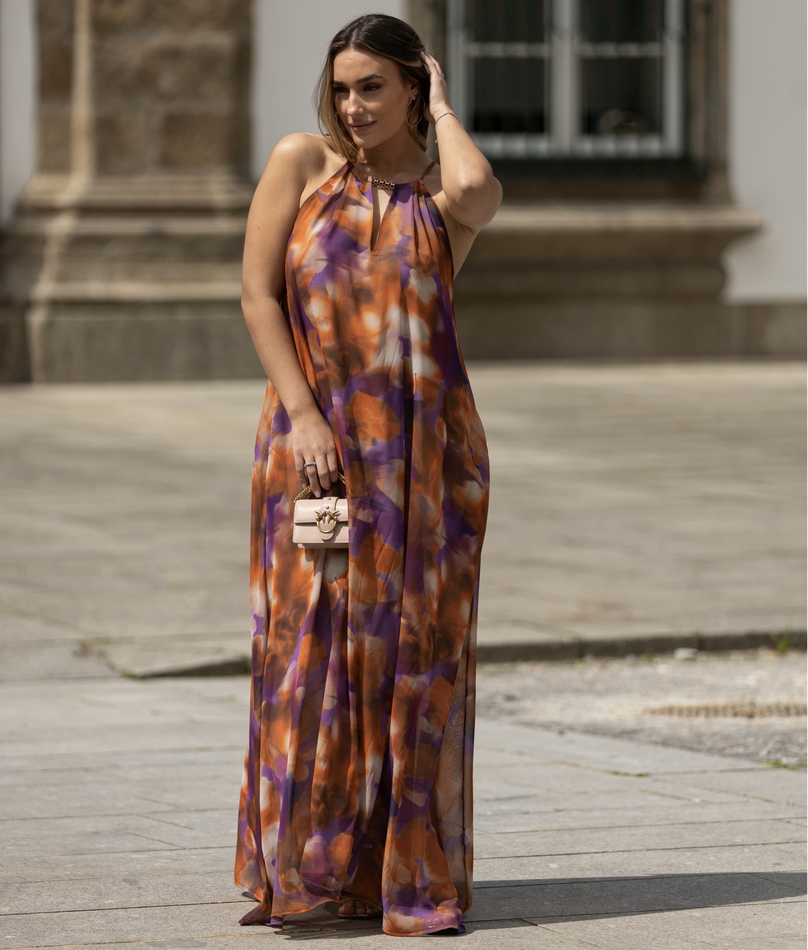 Vestido comprido com padrão Miss You Vestido comprido com padrão colorido abstrato e mala bege em cenário urbano