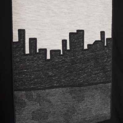 Padrão de cidade a preto e branco com texto RULE THE CITY IKKS em roupa preta.