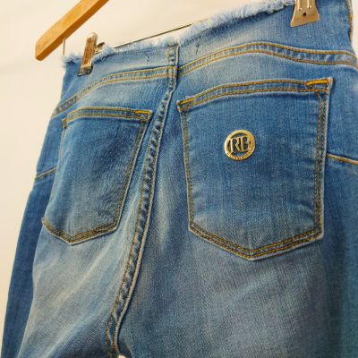 Calças jeans azuis com bolsos traseiros e botão metálico RL penduradas num cabide