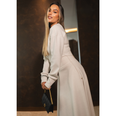 Mulher com conjunto creme e mala preta com corrente dourada