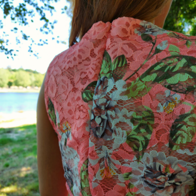 Vestido de renda rosa com padrão floral colorido visto da parte traseira ao ar livre